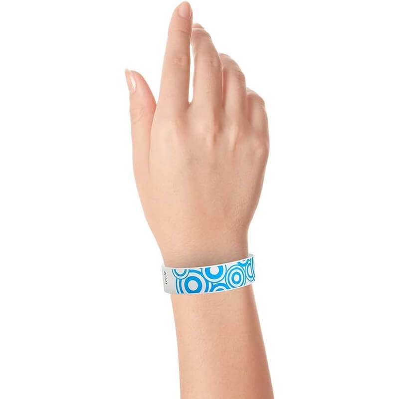 wrist showing a white tyvek wristband with a neon blue disk pattern