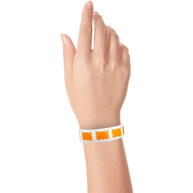 hand wearing a white tyvek wristband with a neon orange burst pattern
