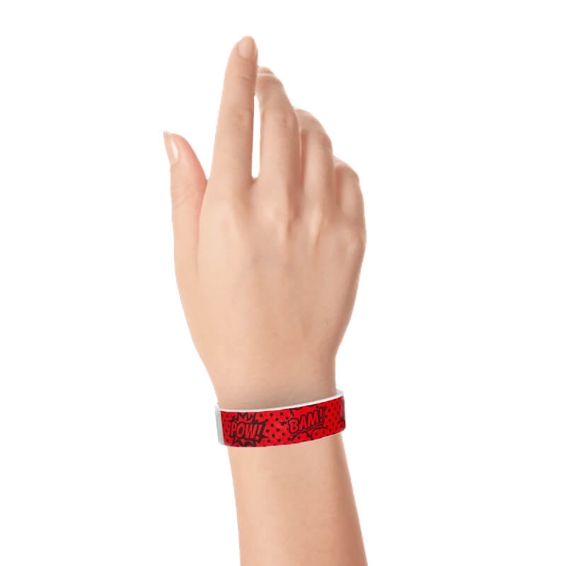 hand wearing a coming superhero pattern in neon red with black design tyvek wristband