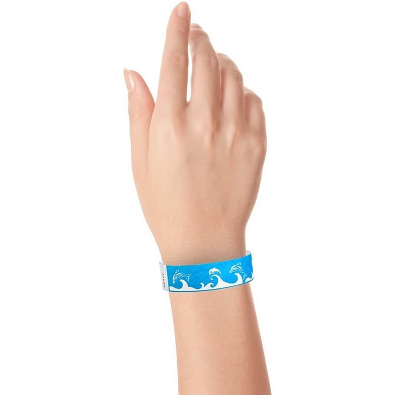 Hand wearing a neon blue wristband with wave & dolphin design in white