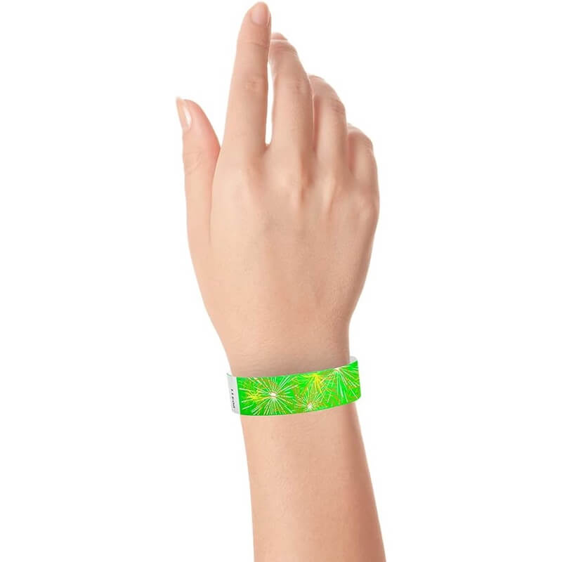 wrist wearing a neon green tyvek wristband with a fireworks pattern in neon yellow, neon orange and white