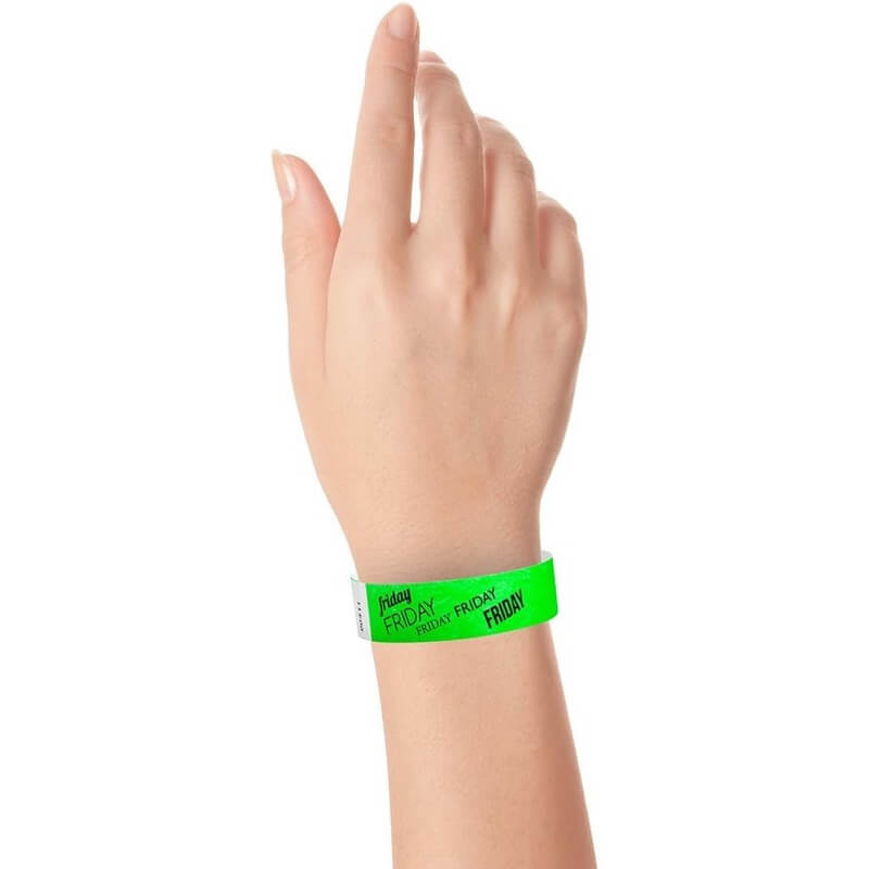 hand wearing neon green tyvek wristband with friday text in black ink repeated