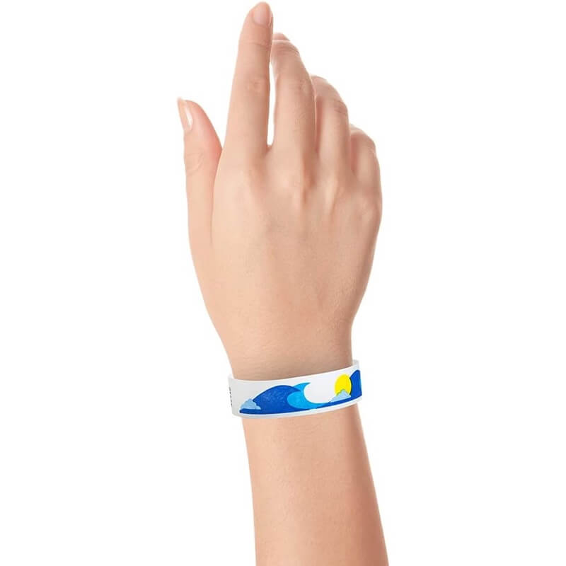 wrist wearing a white tyvek wristband with neon blue and marine blue wave pattern and a neon yellow sun