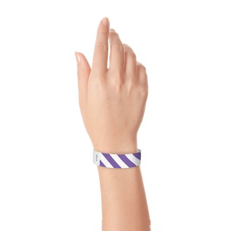 hand wearing white tyvek wristband with purple diagonal stripes