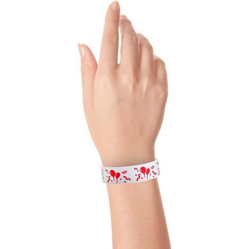 wrist wearing a white tyvek wristband with a neon red balloon pattern