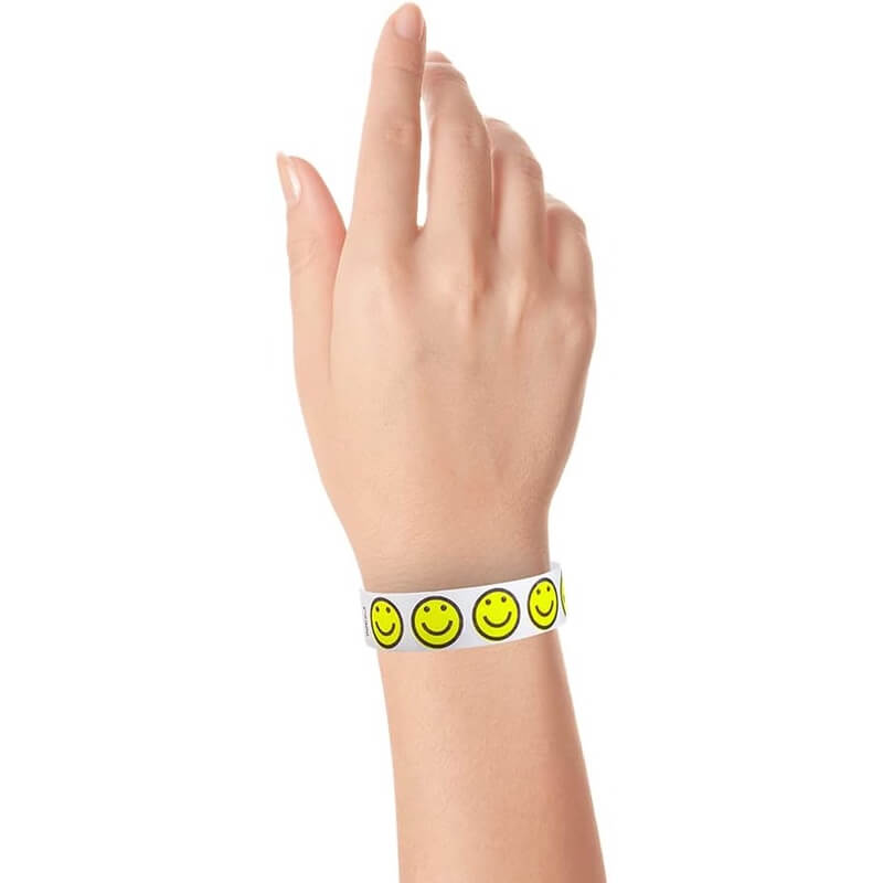 wrist wearing a smiley happyface tyvek wristband - white background and neon yellow and black happyfaces