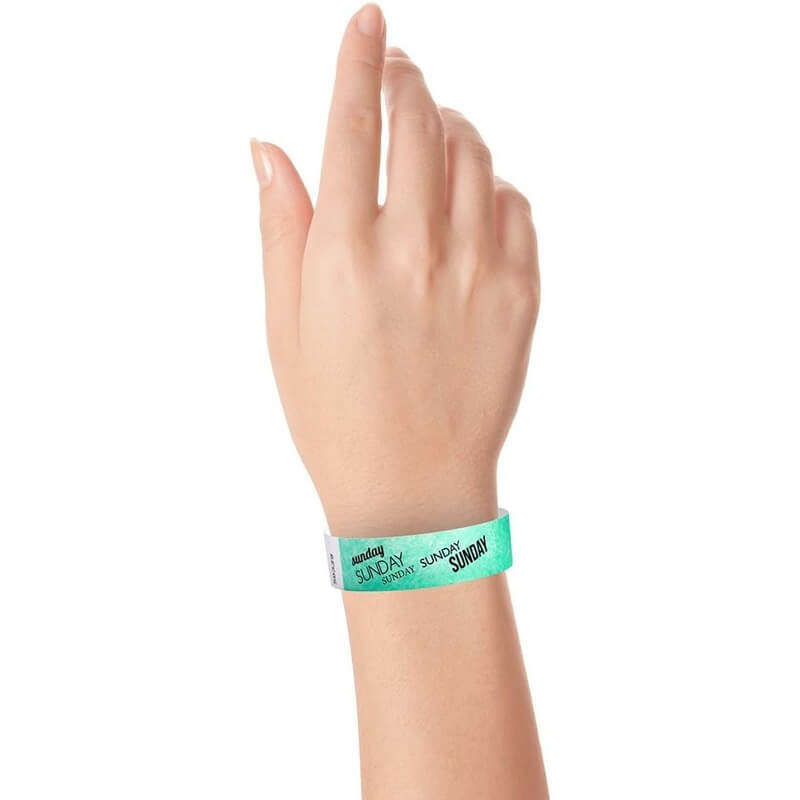 hand wearing an aqua tyvek wristband with sunday text in black ink repeated