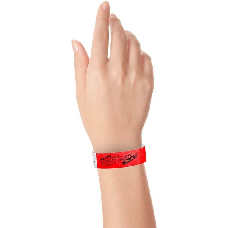 hand wearing neon red tyvek wristband with wednesday text in black ink repeated