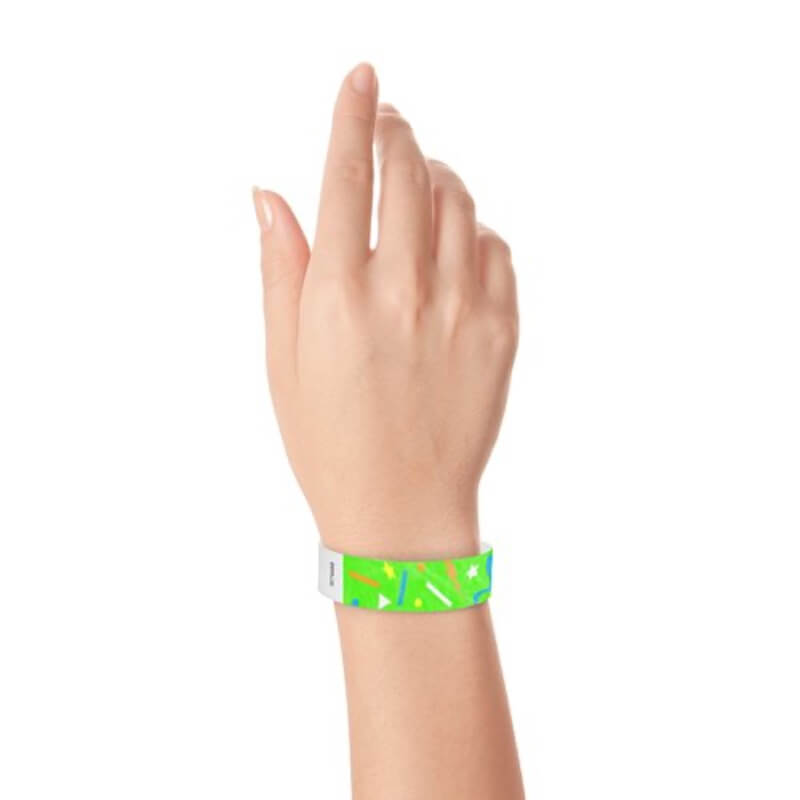 wrist wearing a neon green tyvek wristband in a confetti pattern with neon orange, neon blue, neon yellow and white