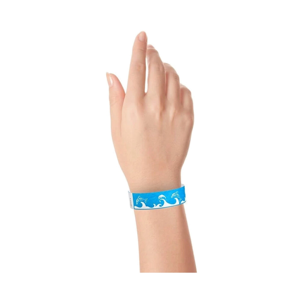 Hand wearing a neon blue wristband with wave & dolphin design in white 