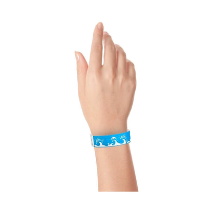 Hand wearing a neon blue wristband with wave & dolphin design in white 