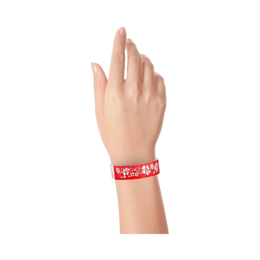 wrist wearing neon red tyvek wristband with white hawaiian flower pattern