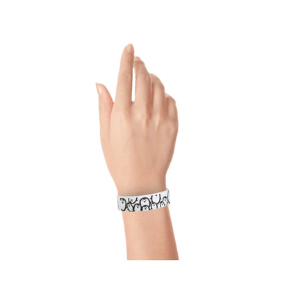 hand wearing a white tyvek wristband with black penguin pattern