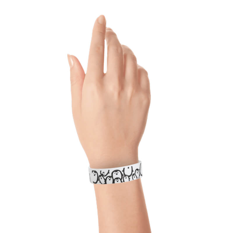hand wearing a white tyvek wristband with black penguin pattern