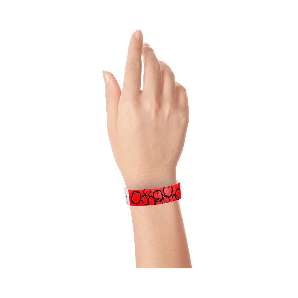 hand wearing a neon red tyvek wristband with a black penguin pattern