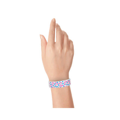Hand wearing a colourful sprinkle pattern in neon pink and neon blue on a white tyvek wristband