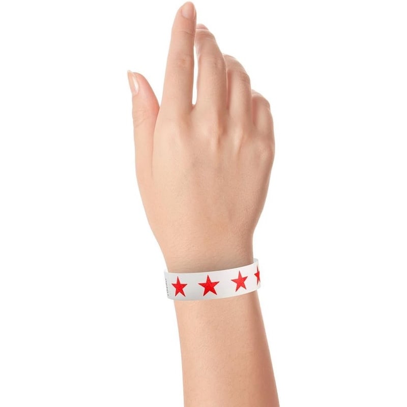 Hand wearing a white tyvek wristband with neon red stars 