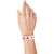 Hand wearing a white tyvek wristband with neon red stars 
