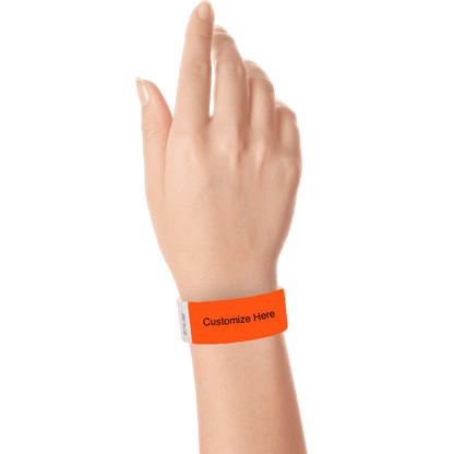 hand wearing a coral red tyvek 1" solid wristband with a placeholder to customize with your text or logo
