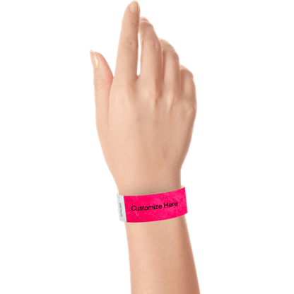 hand wearing a neon pink tyvek 1" solid wristband with a placeholder to customize with your text or logo