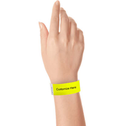 hand wearing a neon yellow tyvek 1" solid wristband with a placeholder to customize with your text or logo