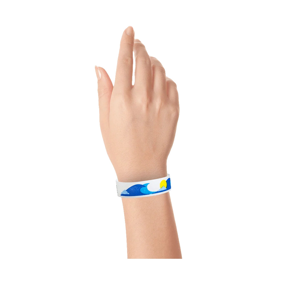 wrist wearing a white tyvek wristband with neon blue and marine blue wave pattern and a neon yellow sun