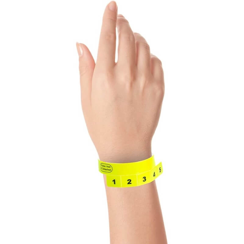 vinyl 5 tab wristbands shown in stock pattern with imprint "stub void if detached" and the number 1-5 on the stubs, shown on hand in neon yellow