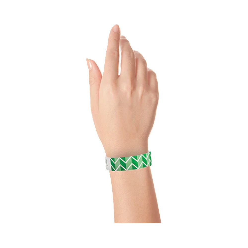 Hand wearing a green and white zig zag patterned tyvek wristband on a white background