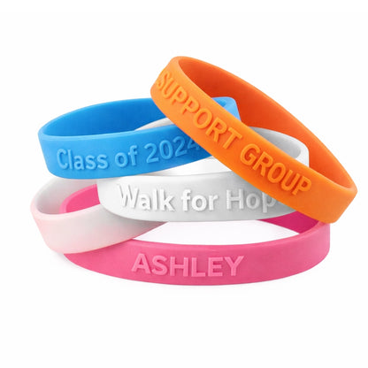 embossed silicone wristbands showing examples of different prints in pink, white, orange and blue